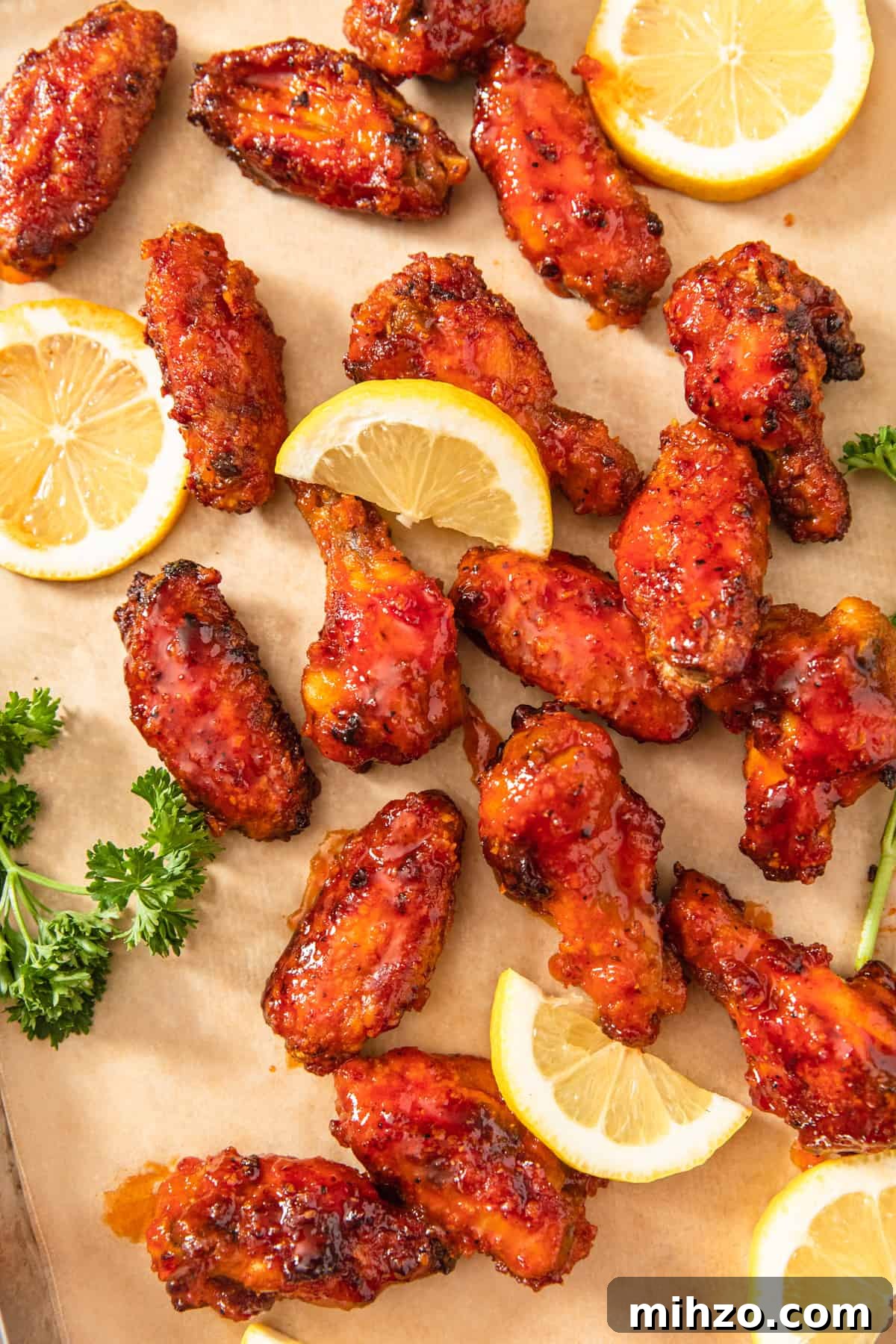 chicken wings on a sheet of parchment paper with lemon slices around them