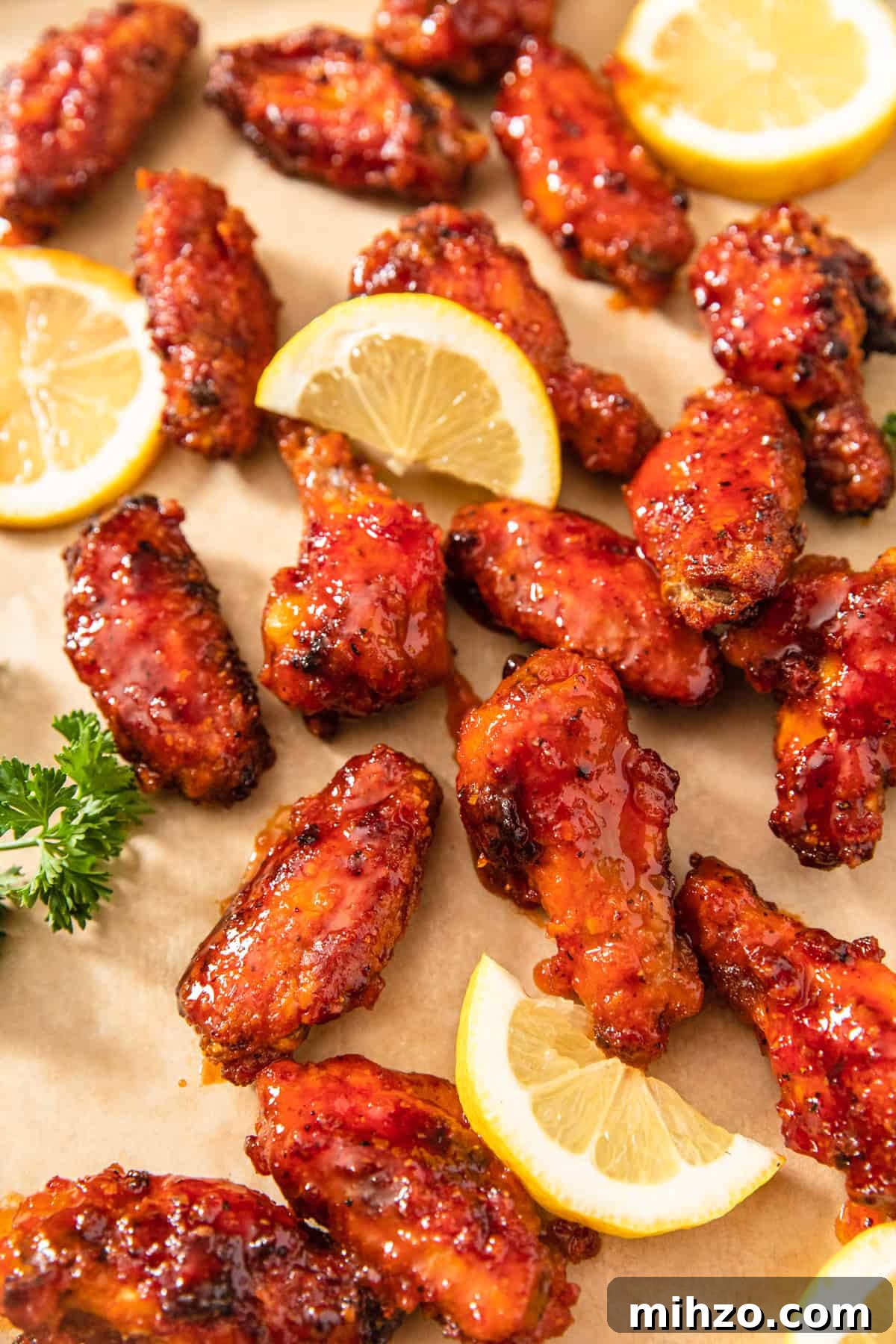 hot chicken wings, lemon slices and parsley on a brown sheet of parchment paper