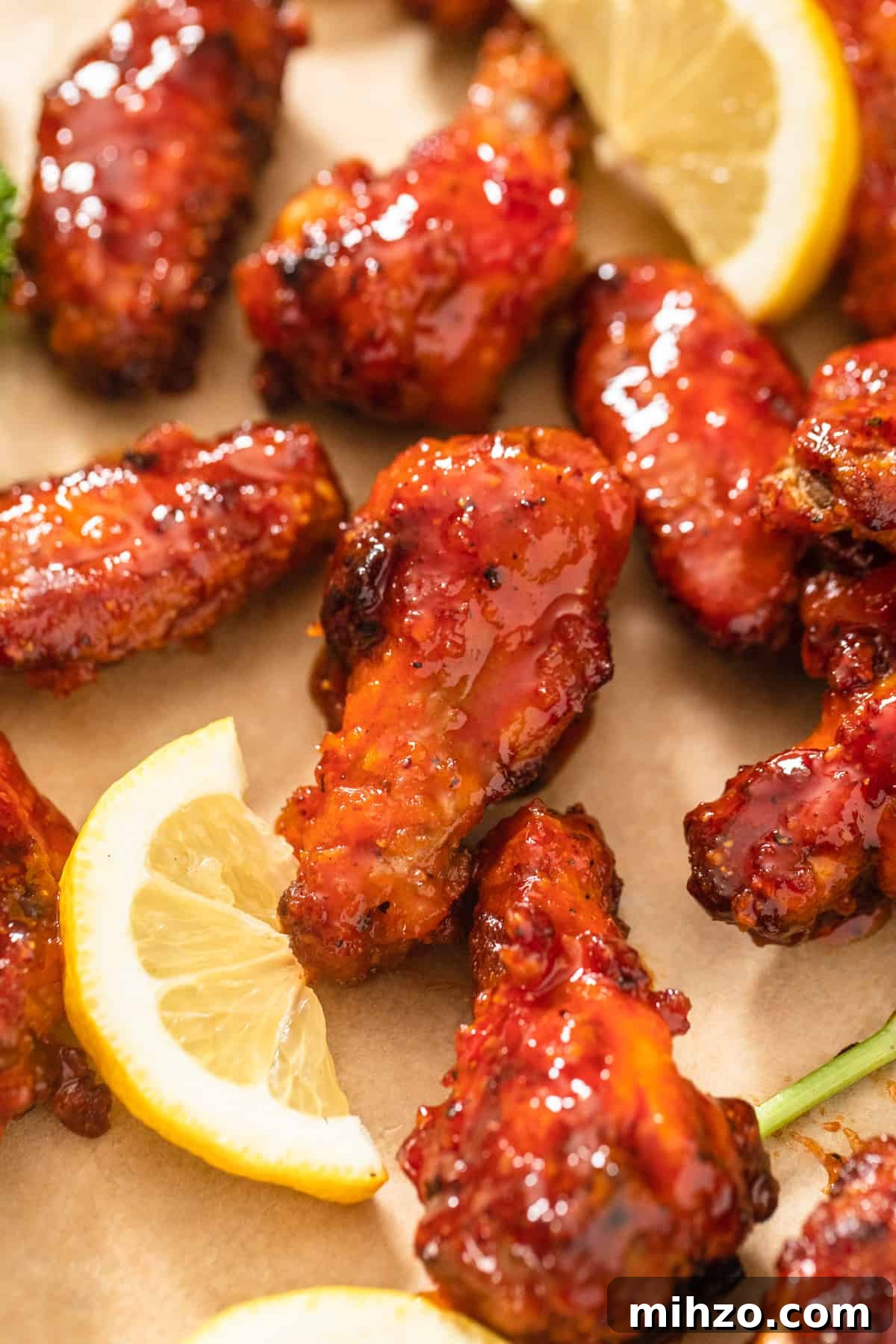 chicken wings on a brown parchment paper sheet with lemon slices beside them