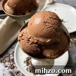 Horizontal image of bowls with scoops of a chocolate frozen dessert on white plates.