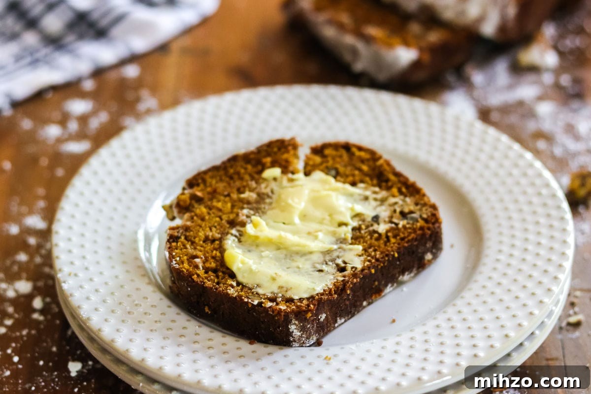 Classic Pumpkin Spice Quick Bread Recipe for Fall Baking 7 A slice of pumpkin spice bread with butter spread on top.