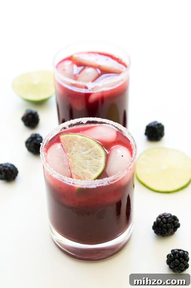 Mixed Berry Margaritas Two Mixed Berry Margaritas in glasses with blackberries and lime wedges as garnish