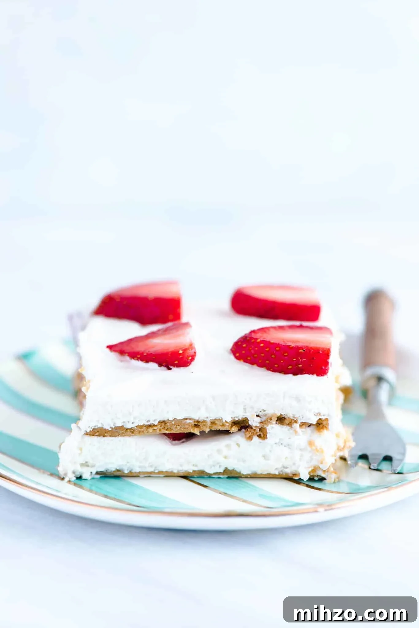 Gluten-Free Strawberry Icebox Cake Recipe for Summer Parties 6 A slice of gluten free strawberry icebox cake on a green and white striped plate