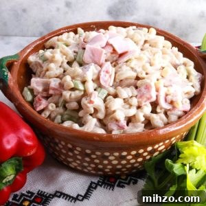 Mexican Macaroni Pasta Salad with Creamy Dressing 8 Ensalada de Coditos in a brown bowl with a red bell pepper and stalk of celery beside it.