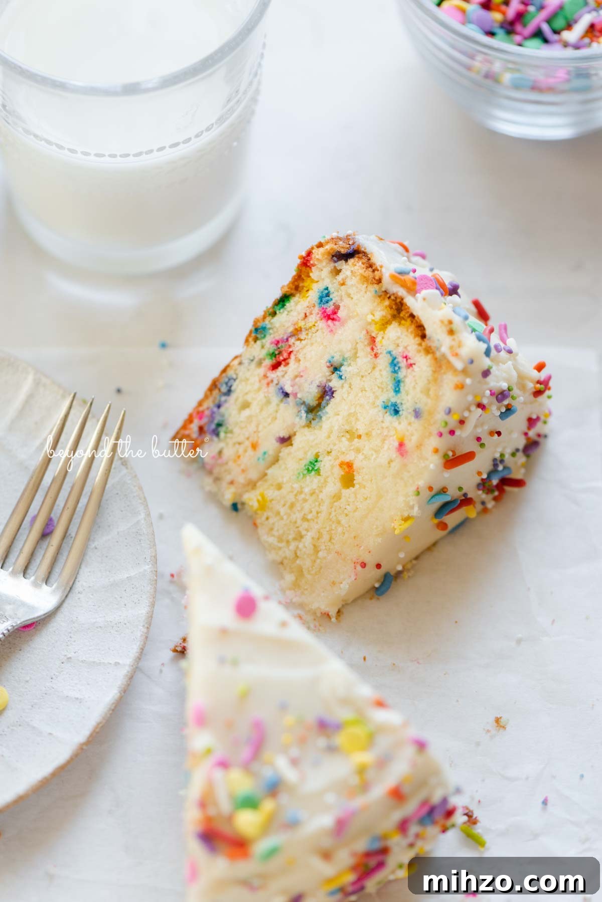 Single-Layer Funfetti Cake Recipe for Bright, Moist Celebration Cakes 13 Slices of single layer funfetti cake on their side with a dessert plate, small fork, and glass of milk nearby from BeyondtheButter.com | All images © Beyond the Butter®