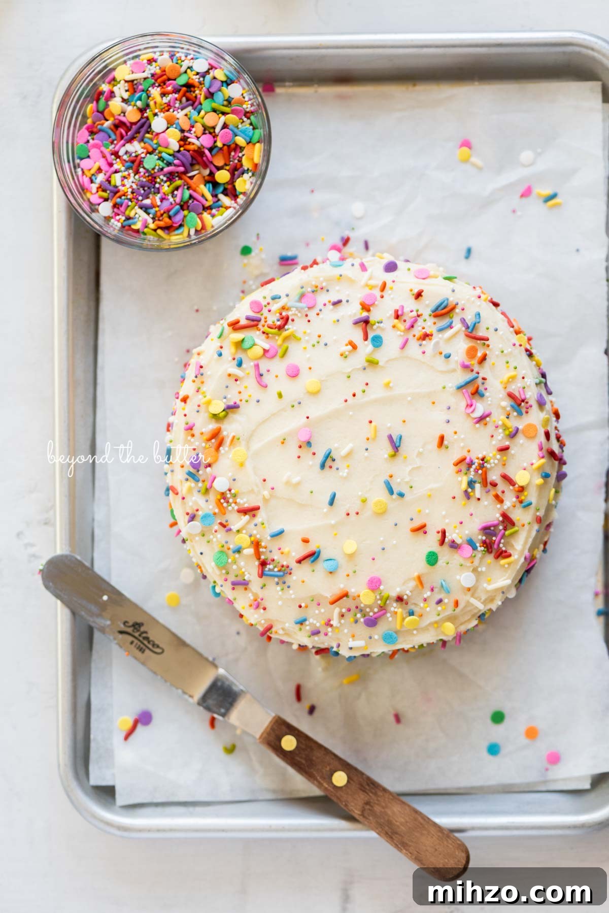 Single-Layer Funfetti Cake Recipe for Bright, Moist Celebration Cakes 4 Single layer funfetti cake just frosted and sprinkled on a small parchment paper lined baking sheet from BeyondtheButter.com | All images © Beyond the Butter®