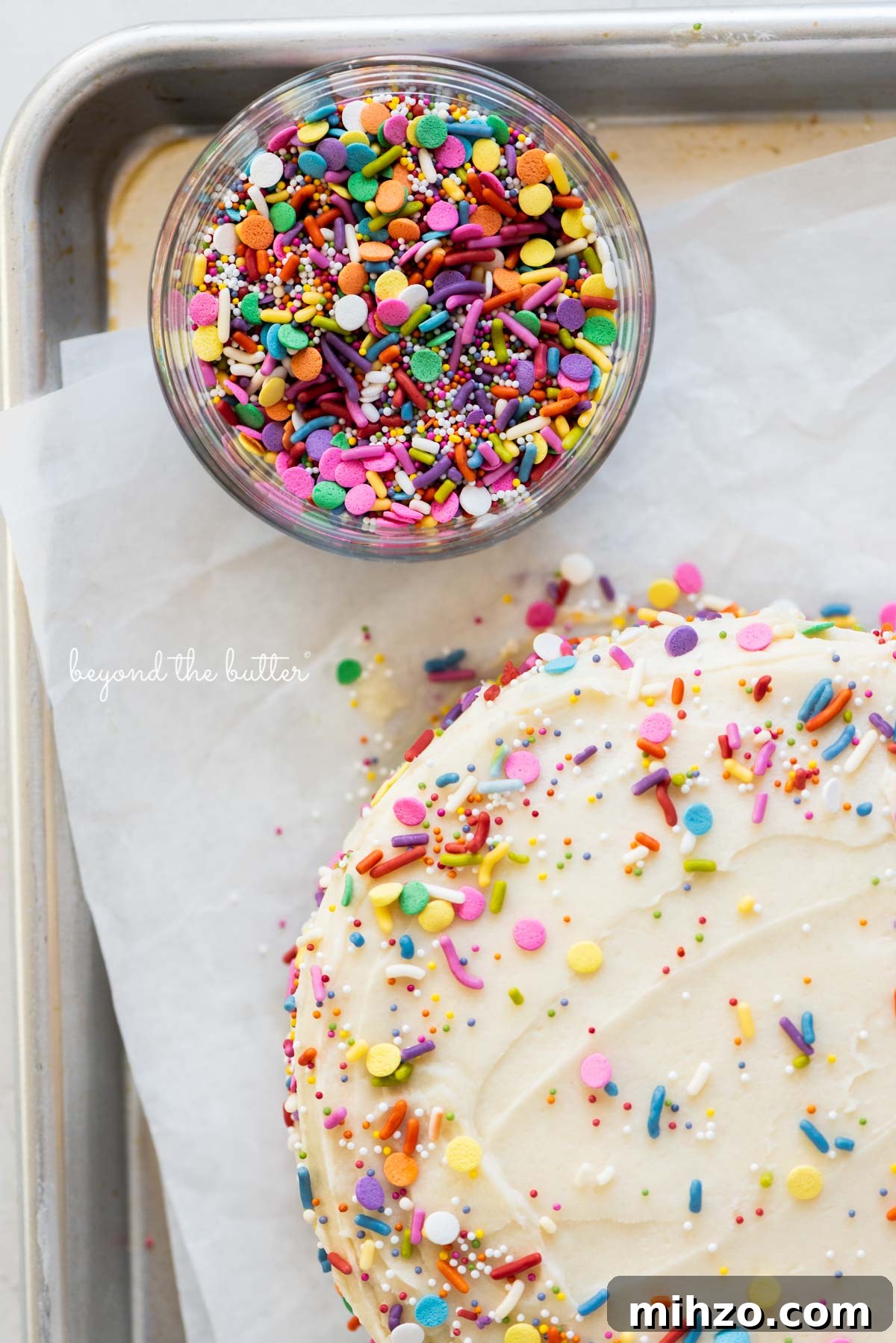 Single-Layer Funfetti Cake Recipe for Bright, Moist Celebration Cakes 9 Close up image of rainbow jimmies and single layer funfetti cake on a parchment paper lined baking sheet from BeyondtheButter.com | All images © Beyond the Butter®