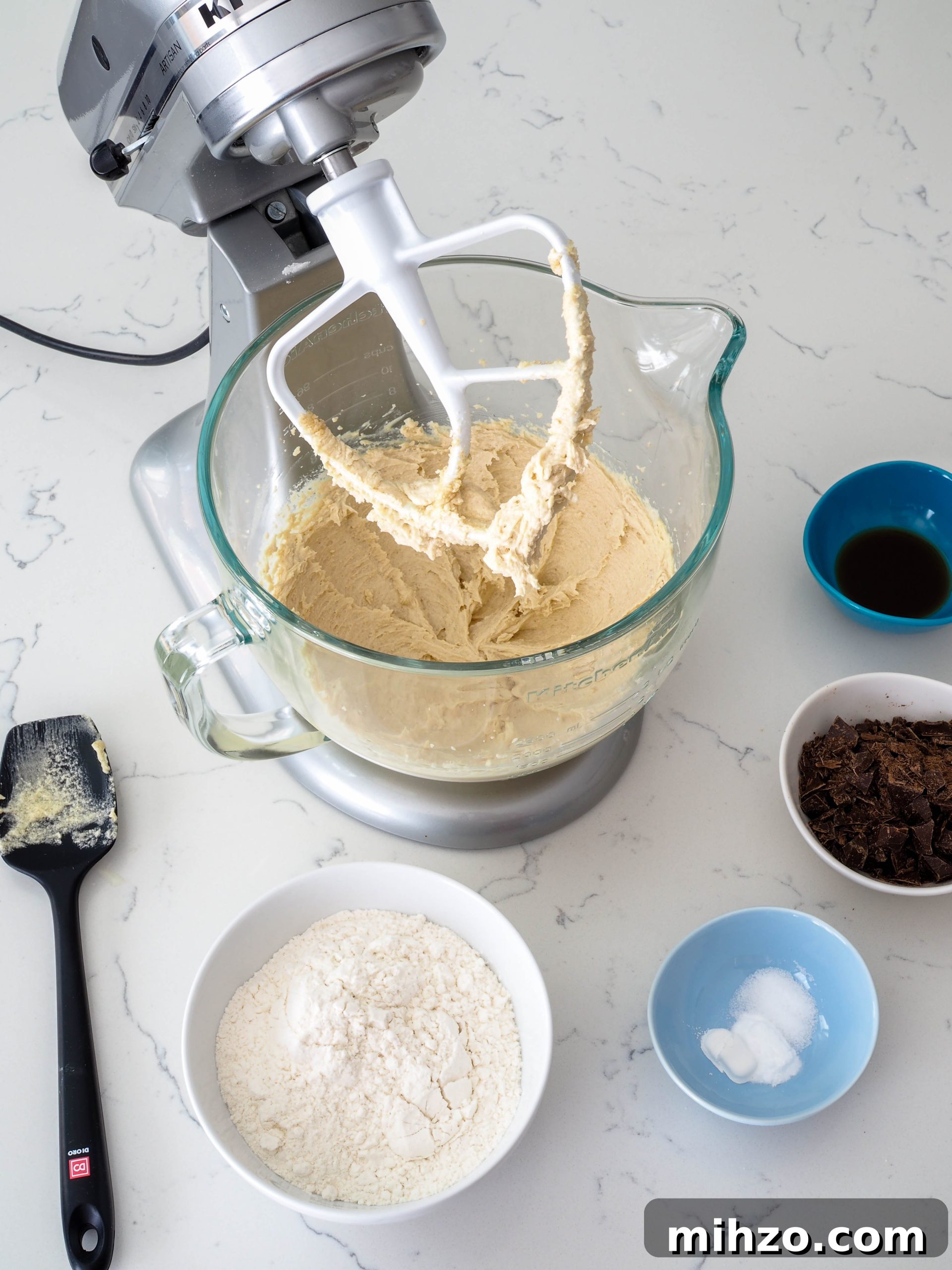 A bowl of cookie dough fitted in a stand mixer, just prior to adding the flour.