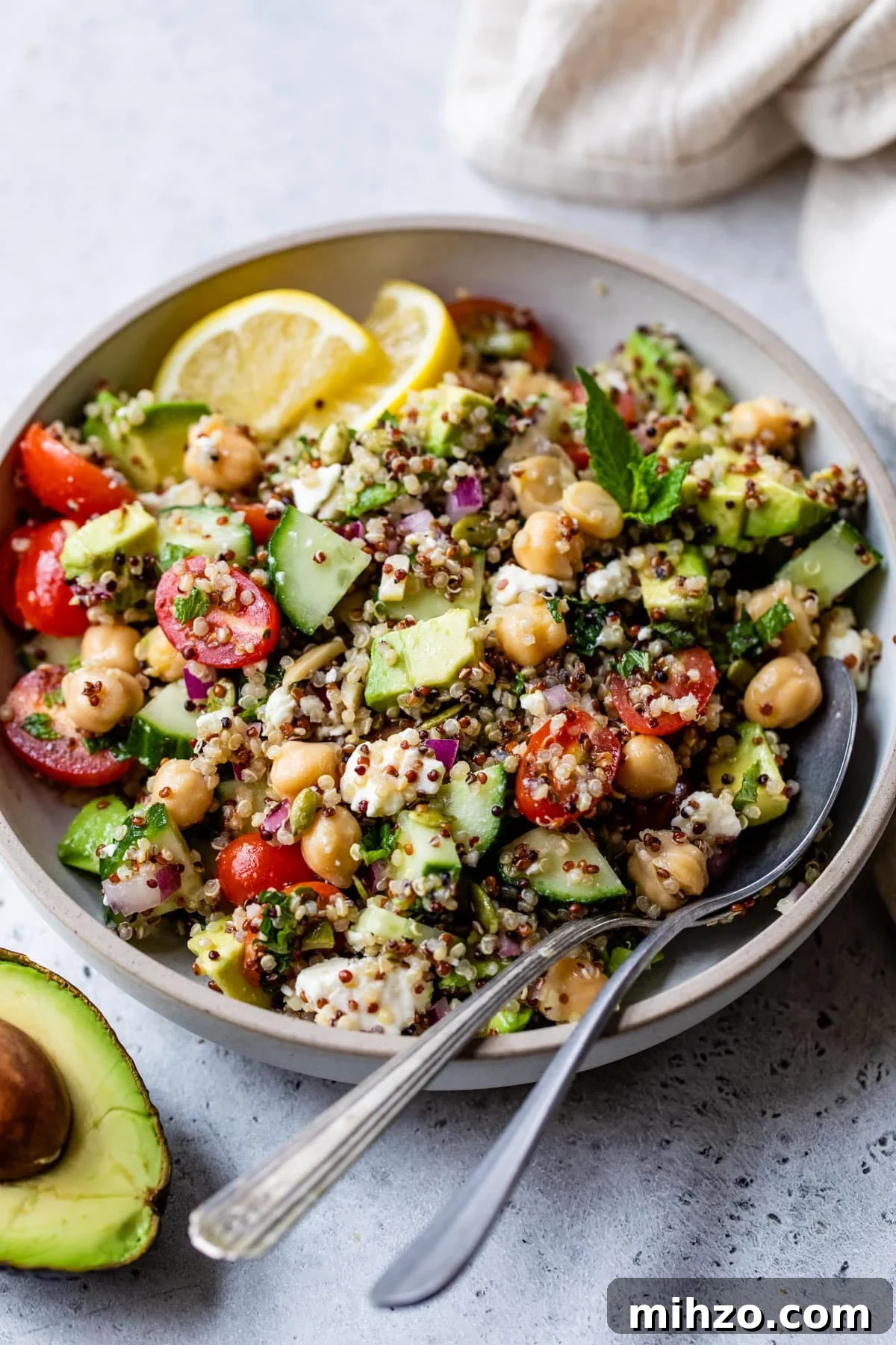 Zesty Lemon Quinoa Salad with Crispy Veggies and Herbs 5 bowl with quinoa, feta cheese, cucumber, and other vegetables inside and with a spoon