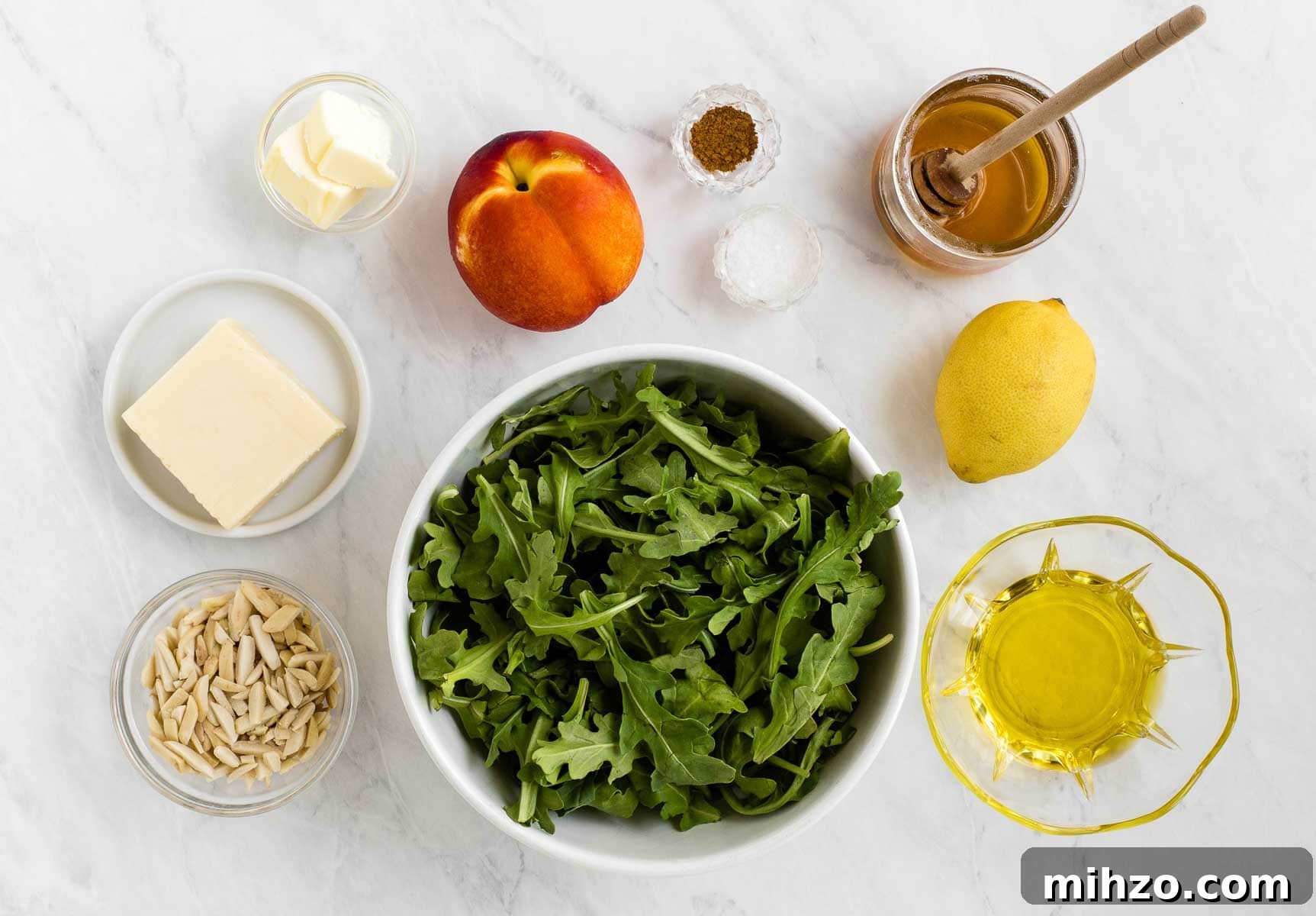 Ingredients for arugula and nectarine salad on a white table.