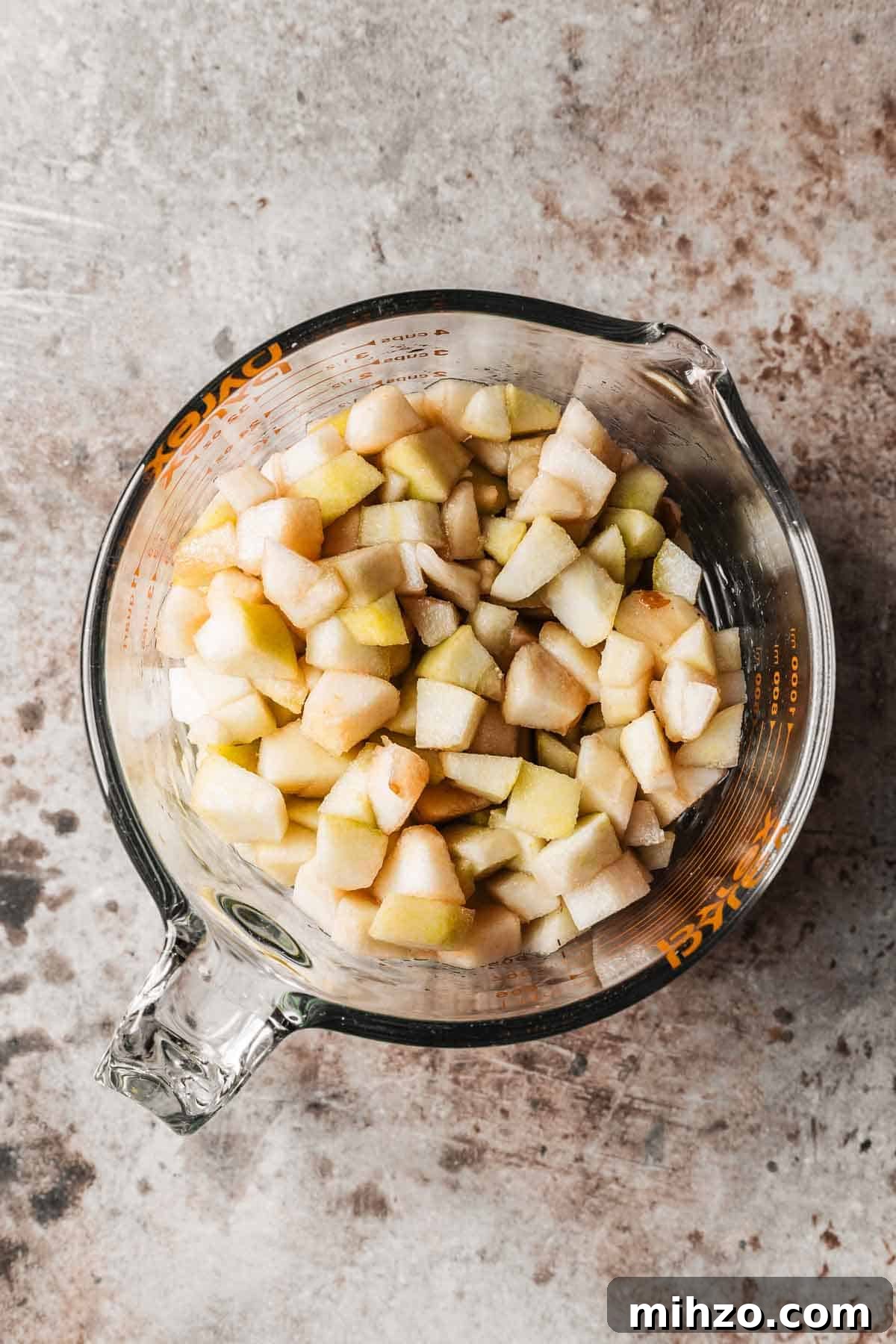 A glass measuring cup with diced pears.