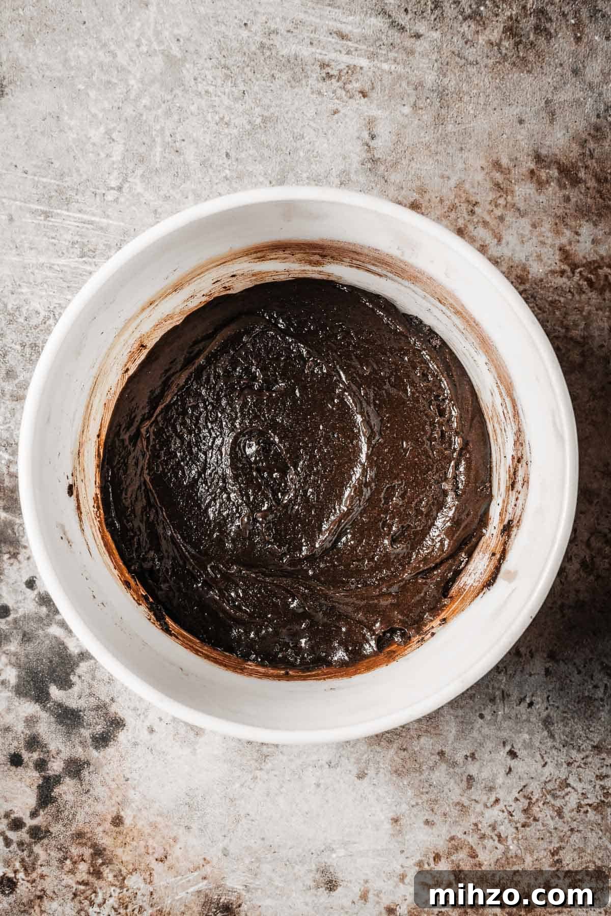 A mixing bowl with wet and dry ingredients fully combined to make a chocolate cake batter.