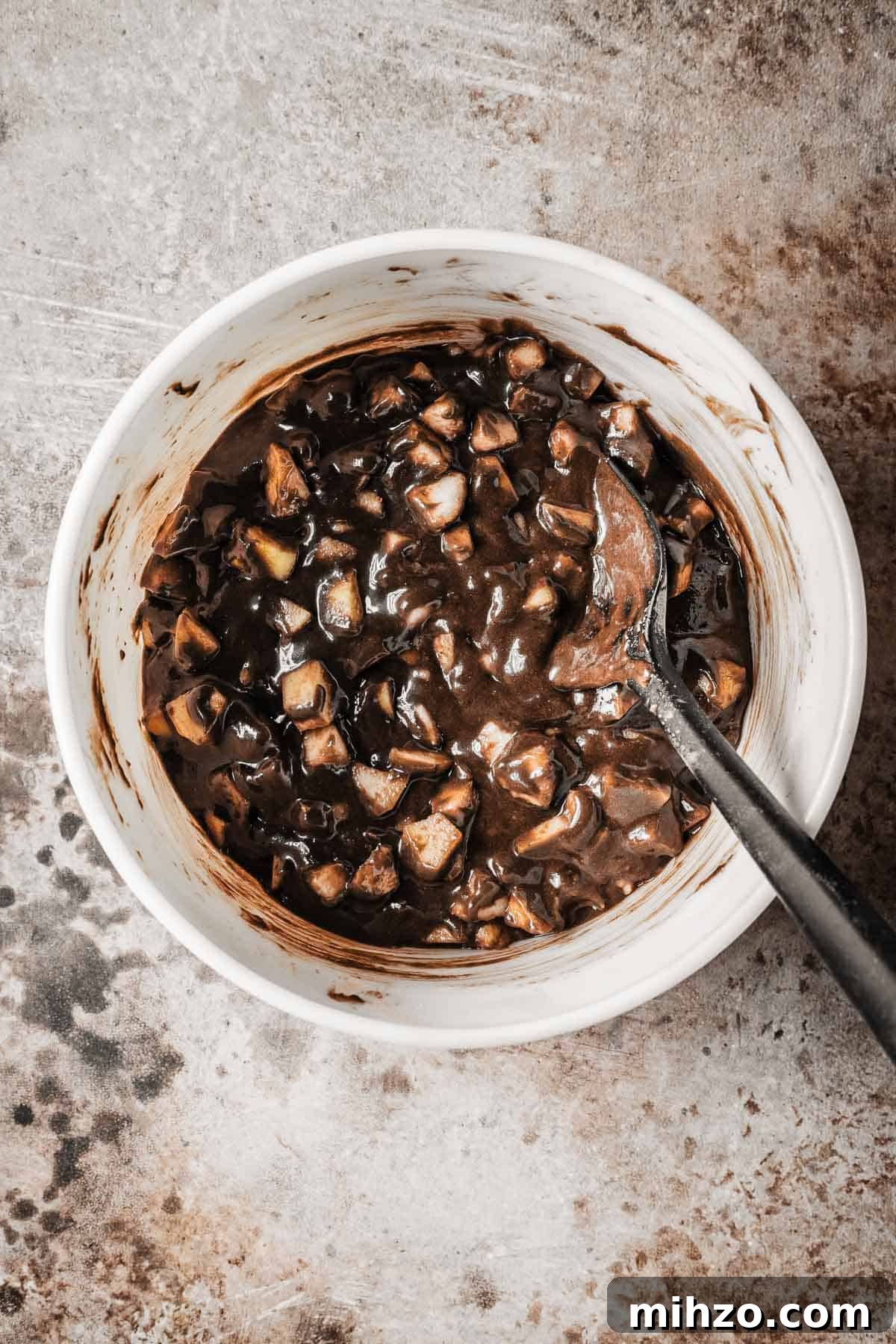 A mixing bowl with diced pears stirred into chocolate cake batter.