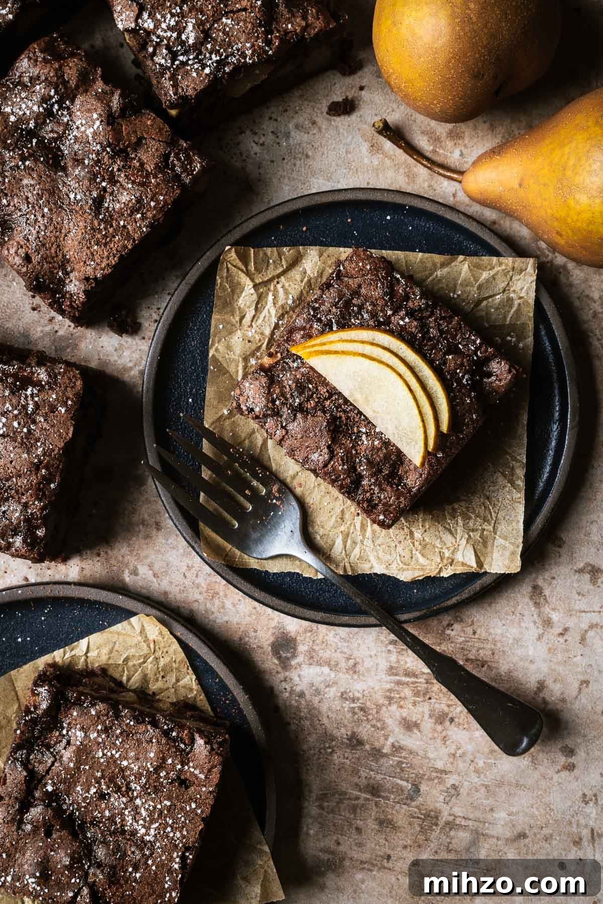 A square of chocolate pear cake on a black ceramic plate.
