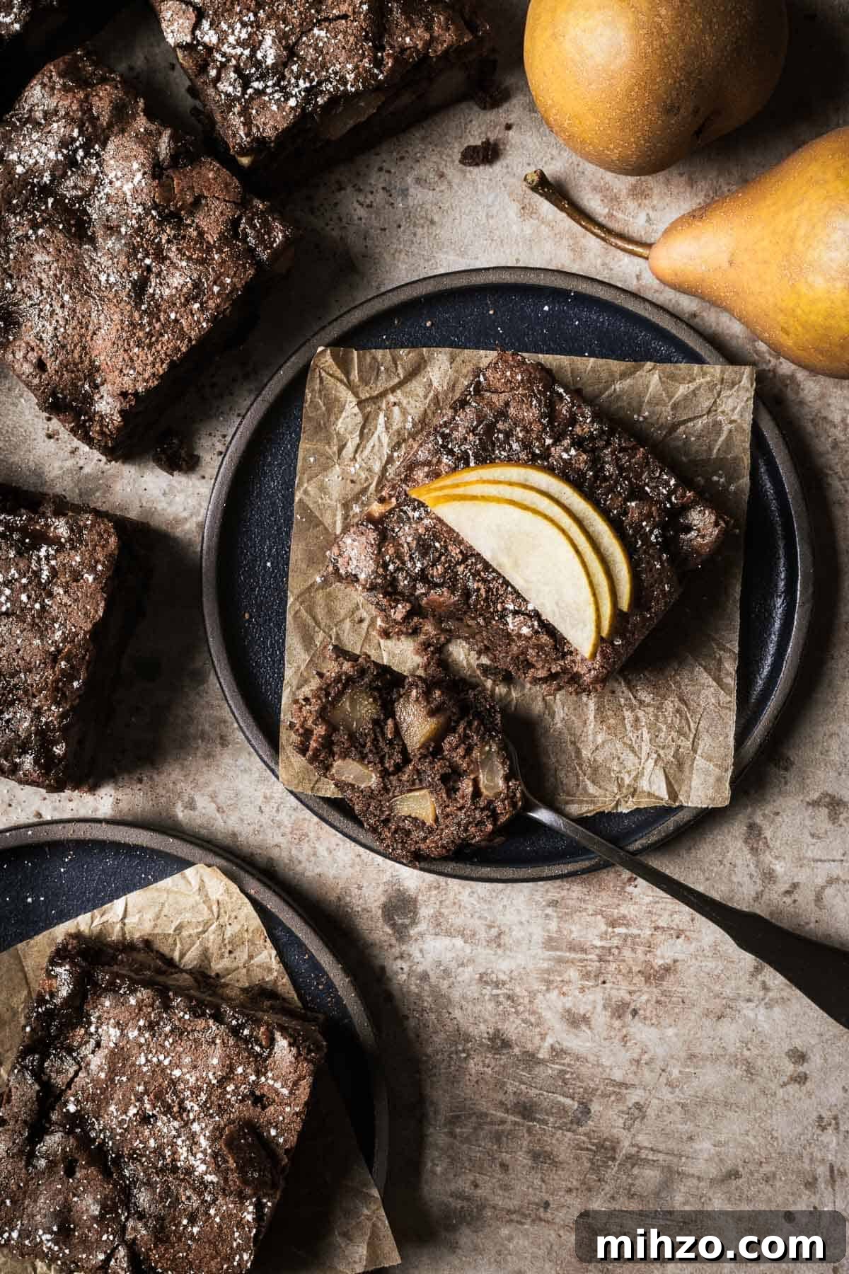 A square of chocolate pear cake with a bite on a fork.