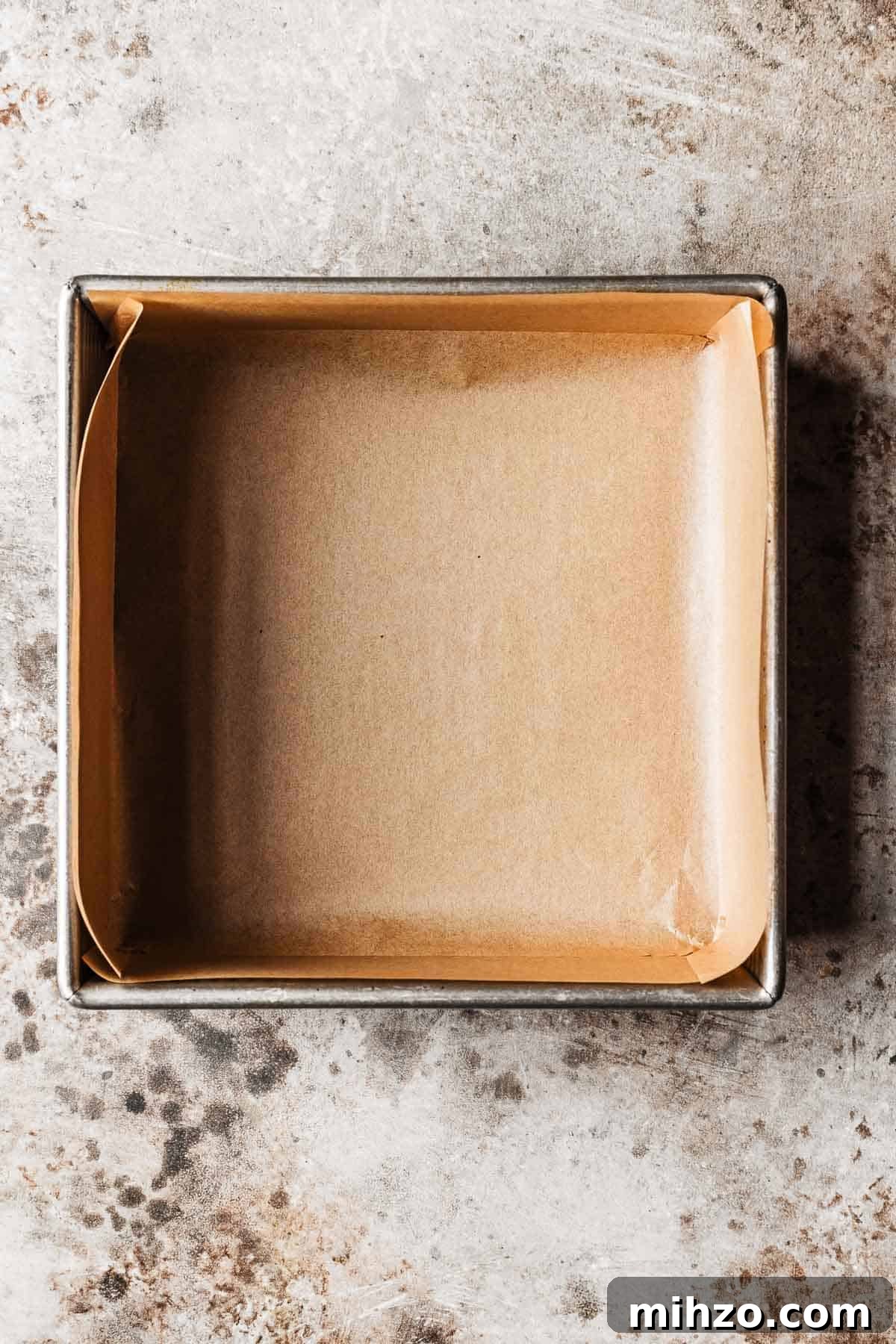 A square metal pan lined with brown parchment paper.