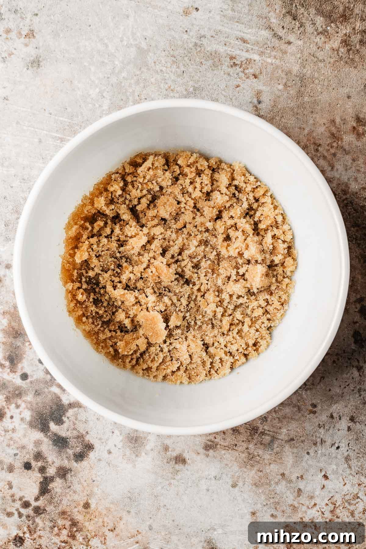 A mixing bowl with brown and white sugars mixed with oil.