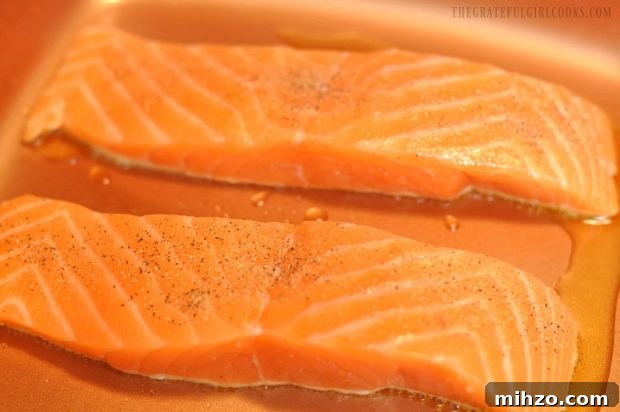 Two salmon fillets searing in copper skillet.
