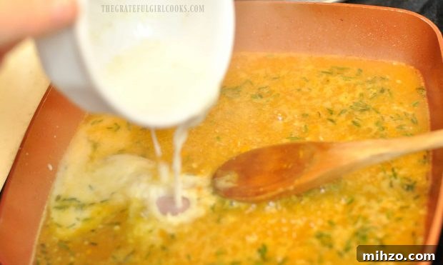 Cornstarch and broth being added to orange sauce in pan.