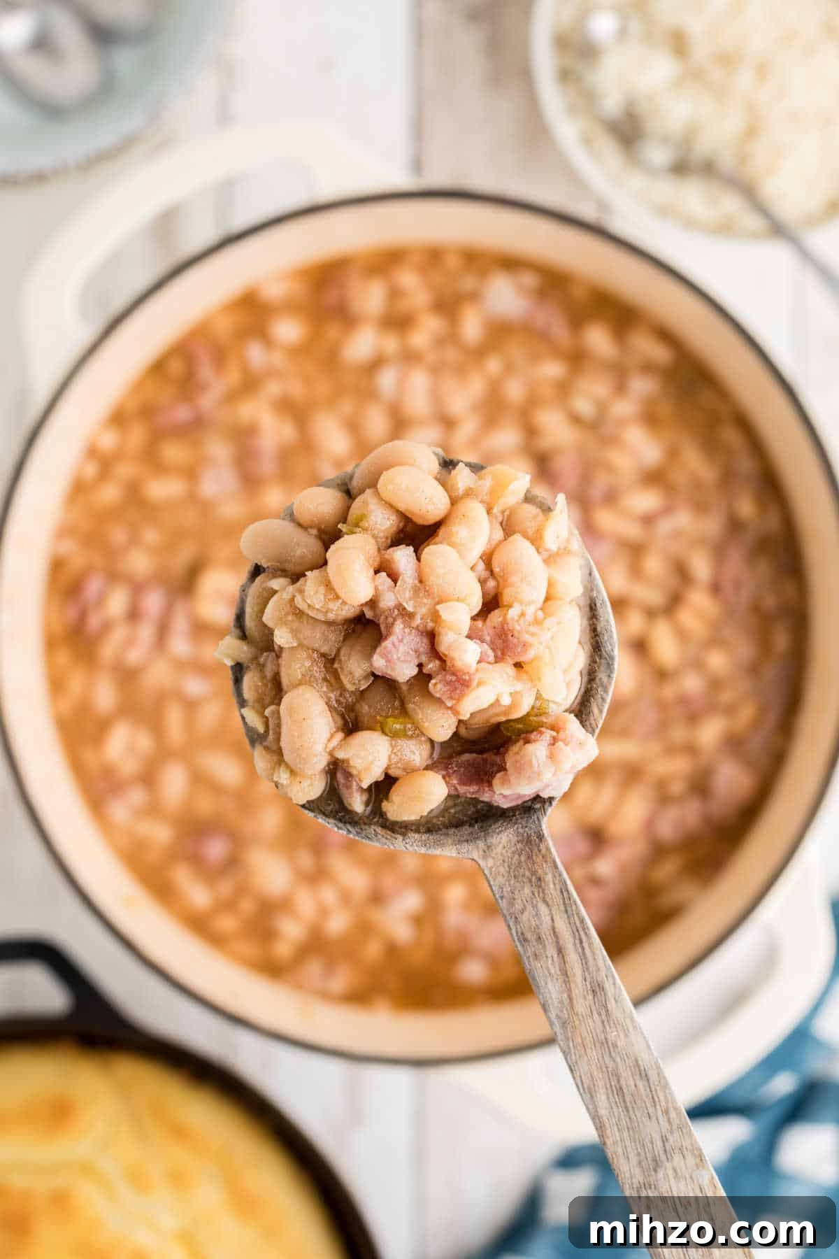 Southern-Style Great Northern Beans Recipe: Savory Slow-Cooker Method 11 Overhead close up shot of a wooden spoon lifting southern great northern beans out of a pot.