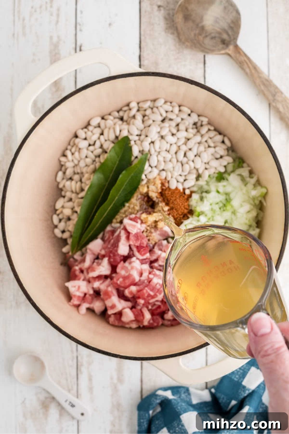 Southern-Style Great Northern Beans Recipe: Savory Slow-Cooker Method 5 Chicken broth being poured into a large Dutch Oven full of ingredients.