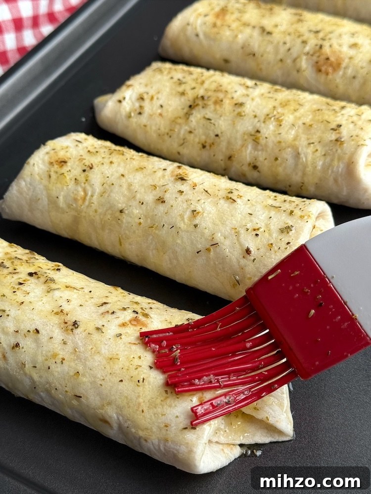 How to Make Pizza Burritos at Home — Fusion Recipe and Tips 7 Pizza burritos on a sheet pan covered in garlic butter ready to go into the oven.