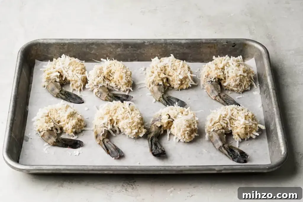 easy coconut shrimp recipe five-spice coconut shrimp dredged and breaded and laying on a baking sheet