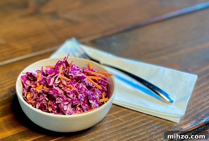 Classic Creamy Homemade Coleslaw Recipe You’ll Love 4 Served in a small bowl with a fork and napkin.