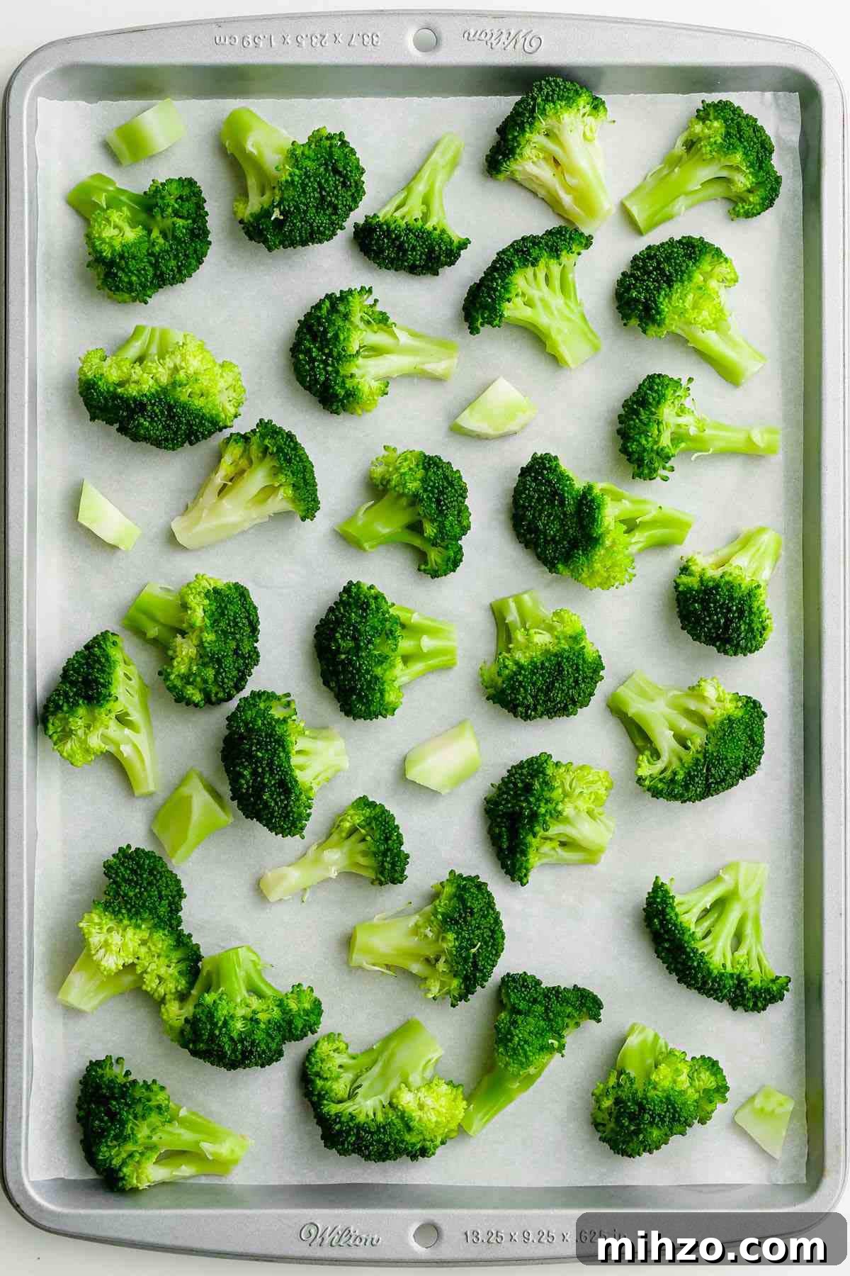 Blanch Broccoli Quickly: Perfectly Crisp, Bright Green Every Time 11 image of scattered broccoli florets on white parchment paper