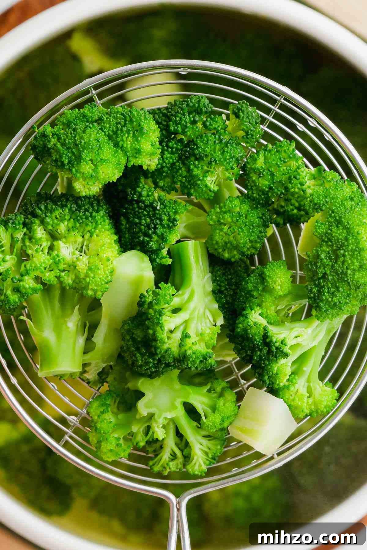 Blanch Broccoli Quickly: Perfectly Crisp, Bright Green Every Time 7 photo of blanched broccoli florets being taken out of water with a sieve