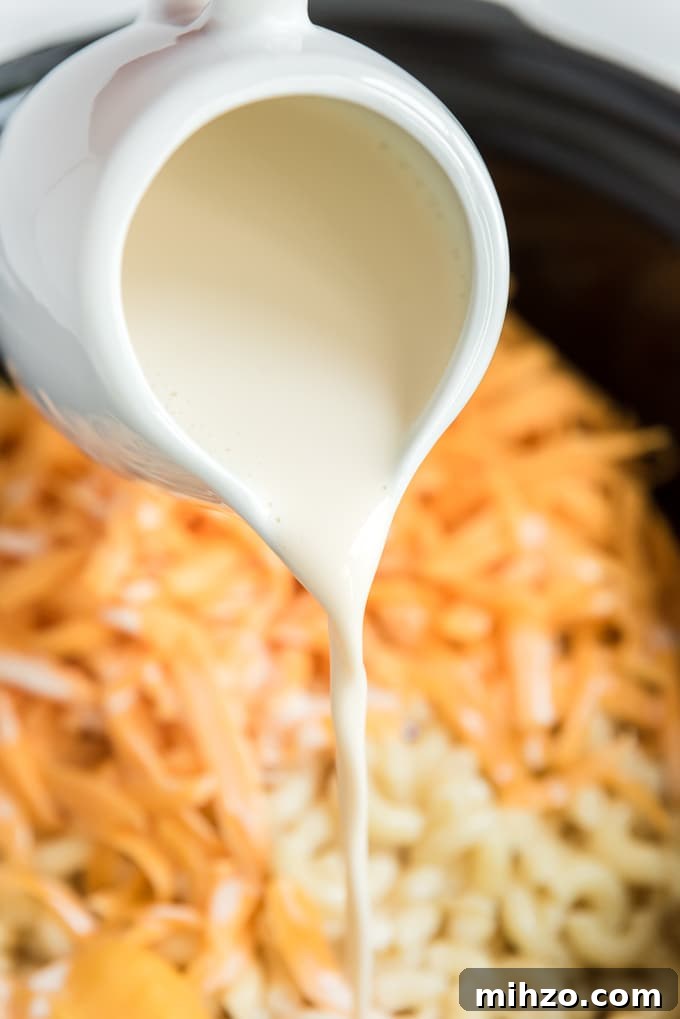 Creamy Slow Cooker Macaroni and Cheese Recipe 4 pouring evaporated milk into crockpot