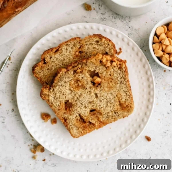 Two slices of Banana Bread on a small white plate with a cup of milk and a small cup of butterscotch chips on the side.
