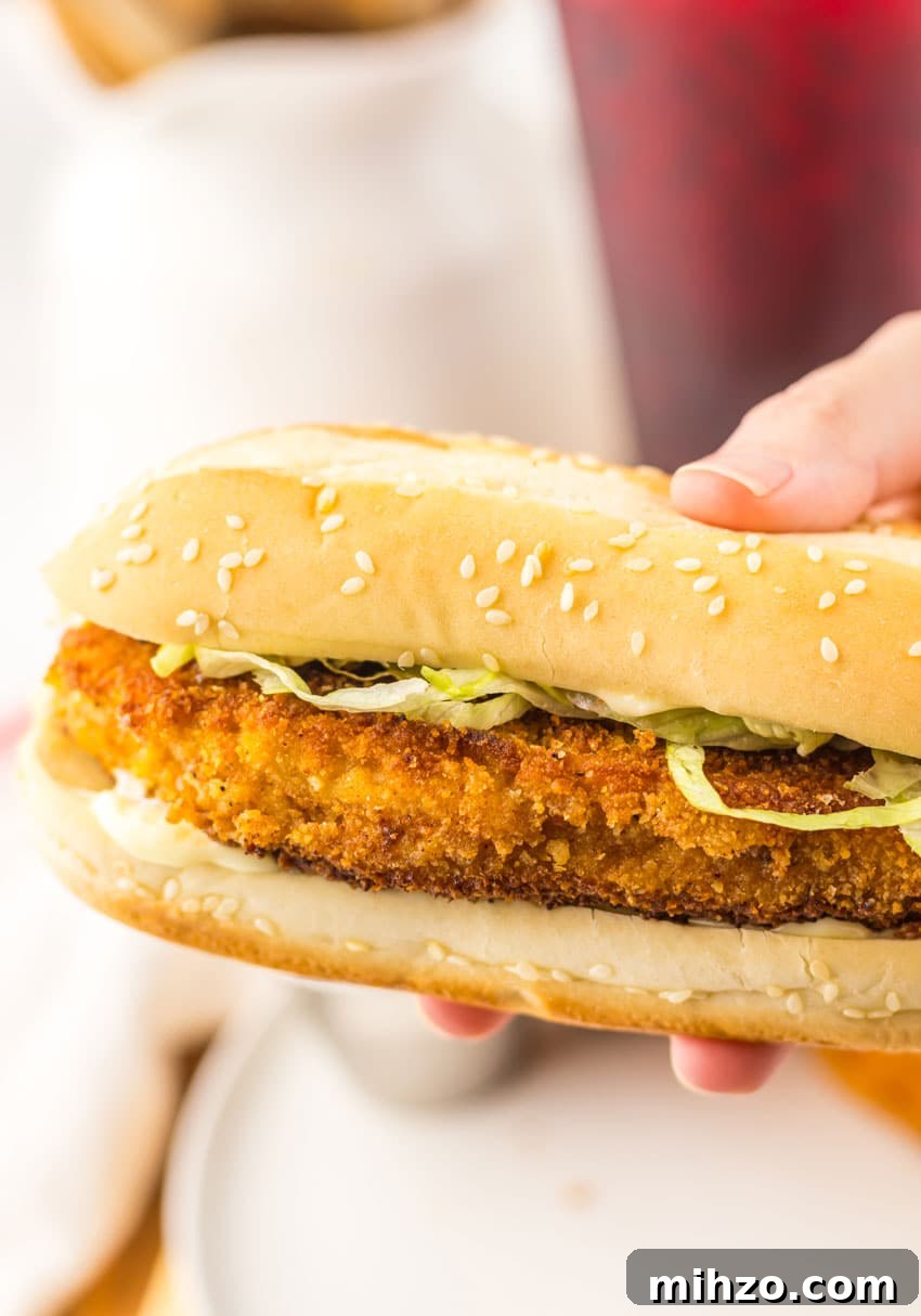 a hand holding up a copycat burger king original chicken sandwich
