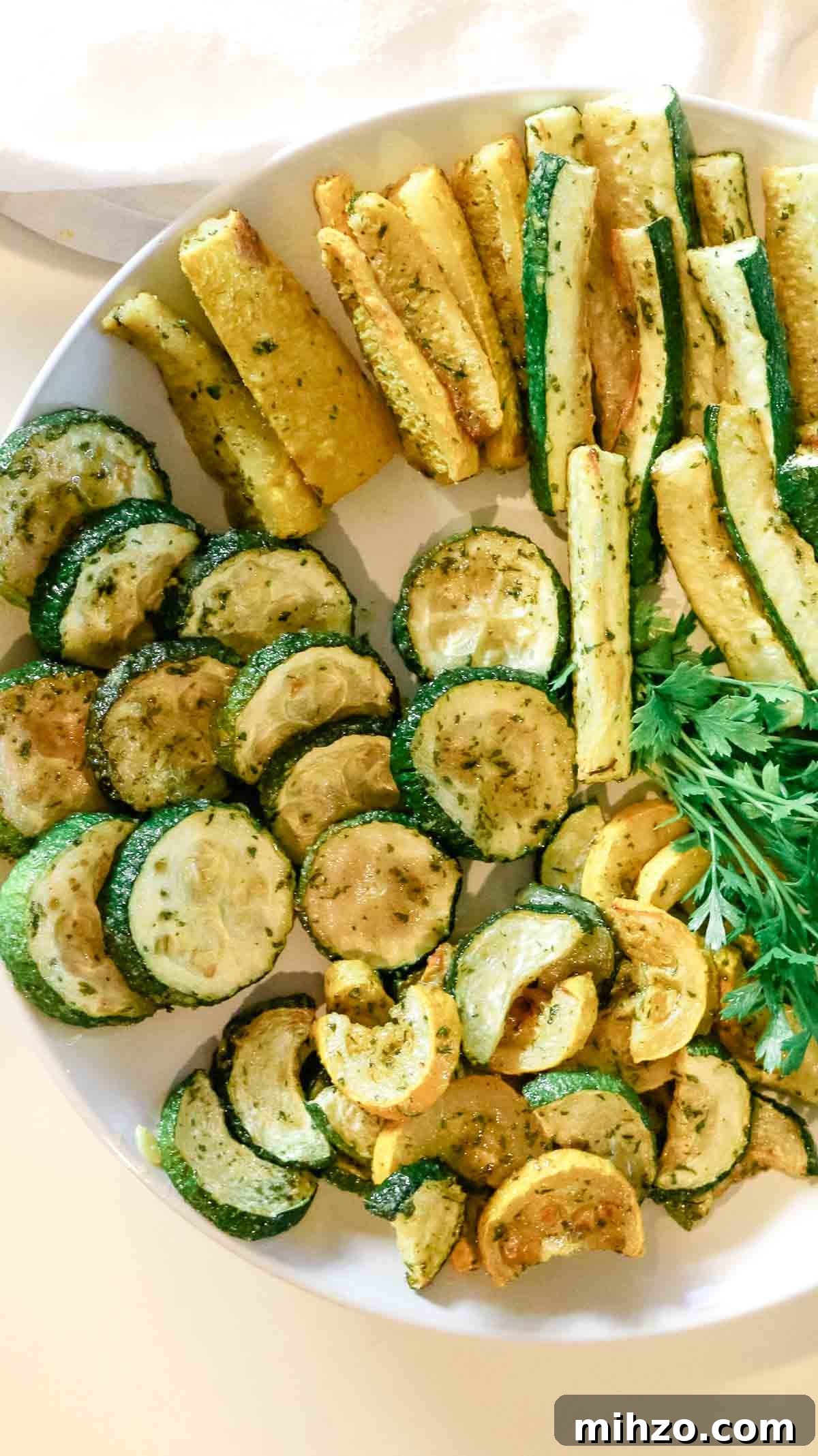 roasted zucchini rounds and zucchini fries on a white plate.