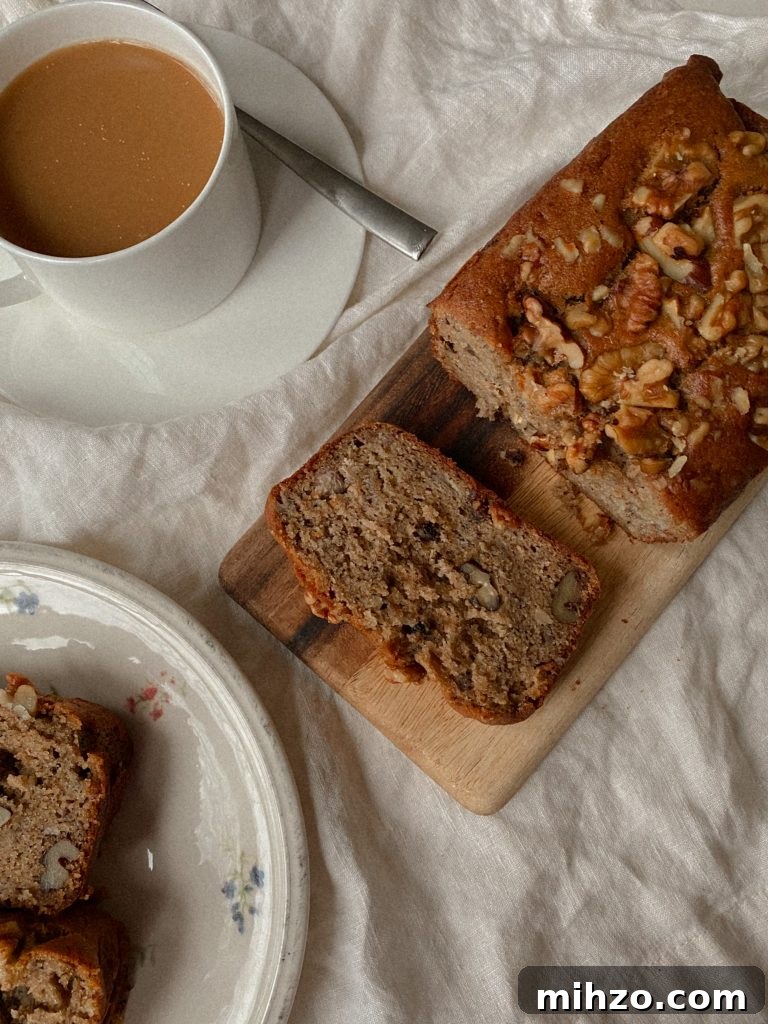 Gluten-Free Banana Bread Recipe That Actually Tastes Great 2 walnut banana bread sliced on a wood board with white mug of coffee and slices on a plate