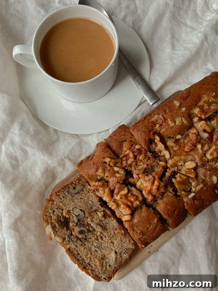 Gluten-Free Banana Bread Recipe That Actually Tastes Great 3 walnut banana bread sliced on a wood board with white mug of coffee