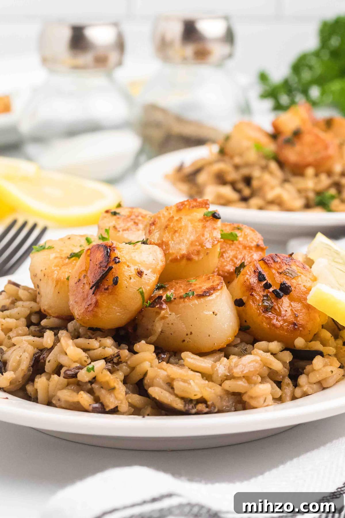 pan seared scallops on plate with brown rice and lemons