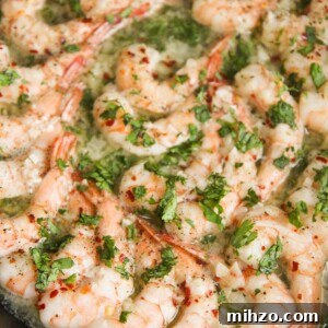 Garlic Butter Baked Shrimp Scampi Recipe for Dinner 5 baked shrimp with parsley in a cast iron skillet up close.