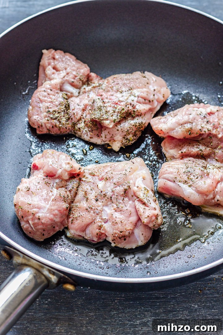 Creamy Garlic Boneless Skinless Chicken Thighs Recipe 4 Boneless chicken thighs browning in olive oil in a skillet.
