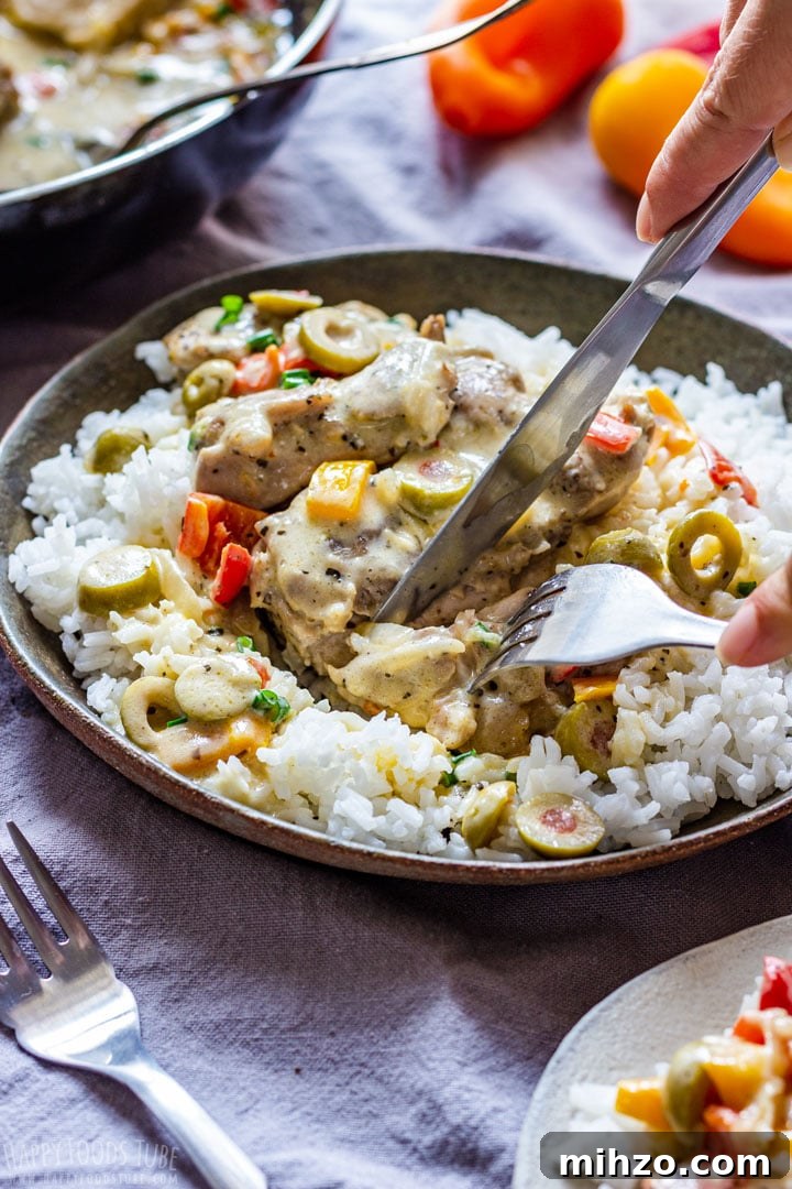 Creamy Garlic Boneless Skinless Chicken Thighs Recipe 7 Creamy chicken thighs served over rice with olives and peppers, being cut with a knife and fork.