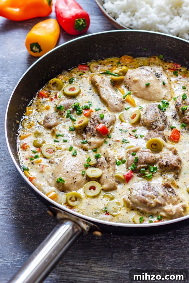 Creamy Garlic Boneless Skinless Chicken Thighs Recipe 8 Creamy boneless skinless chicken thighs in a skillet with olives and peppers, with rice in the background.