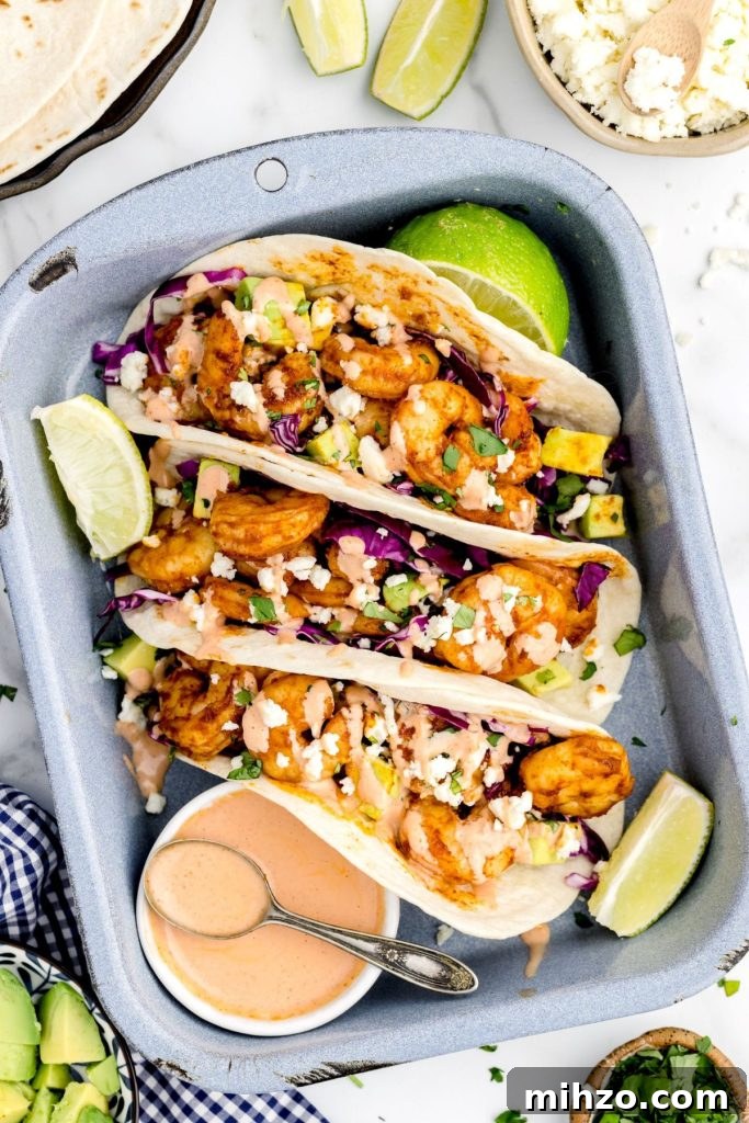 Crispy Air Fryer Shrimp Tacos with Lime Slaw and Spicy Mayo 2 Golden seasoned shrimp in tortillas with lime wedges and toppings.