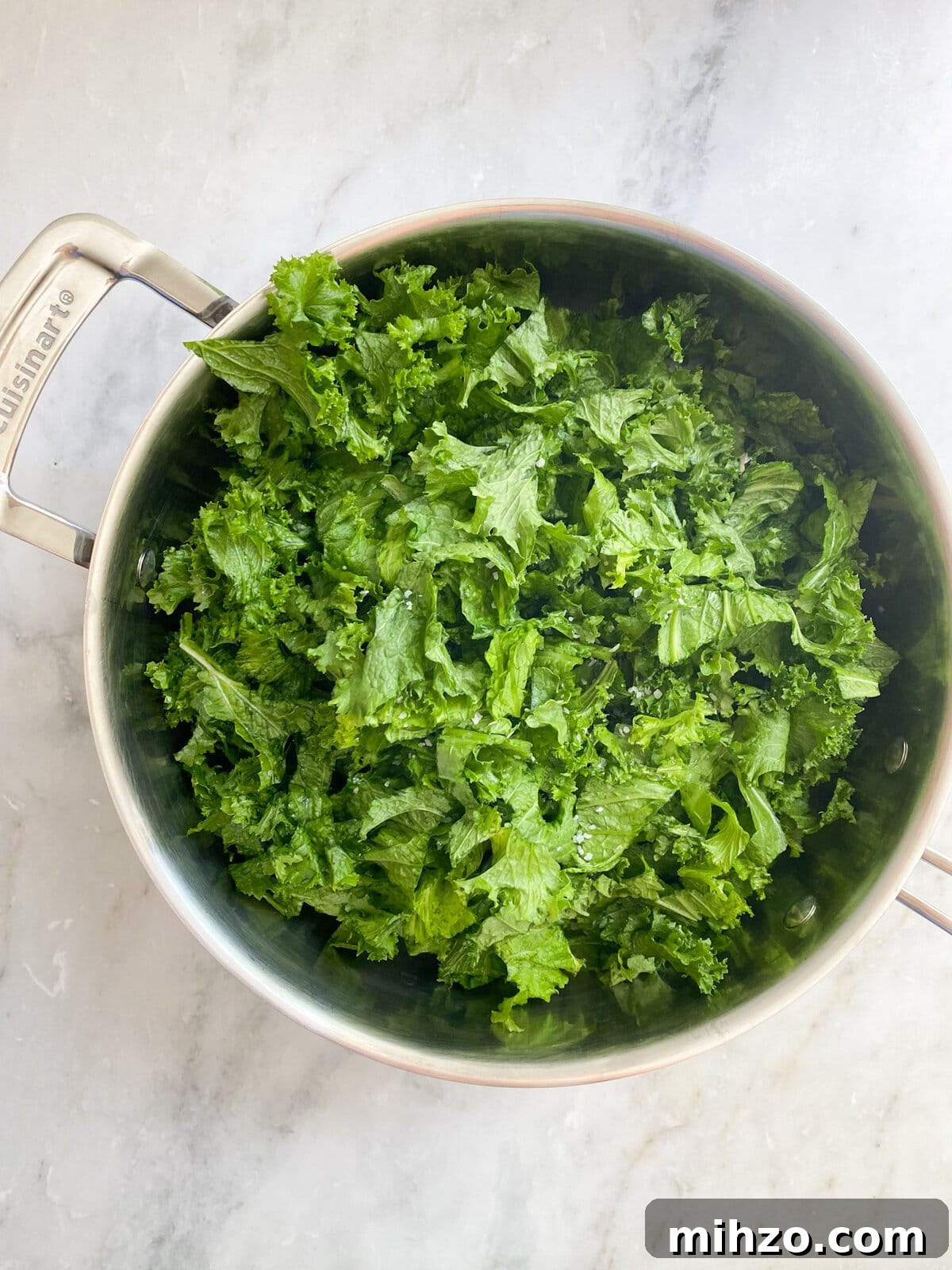Adding escarole to pan with garlic and cooking.