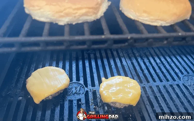 frozen burgers finishing on the grill with buns toasting