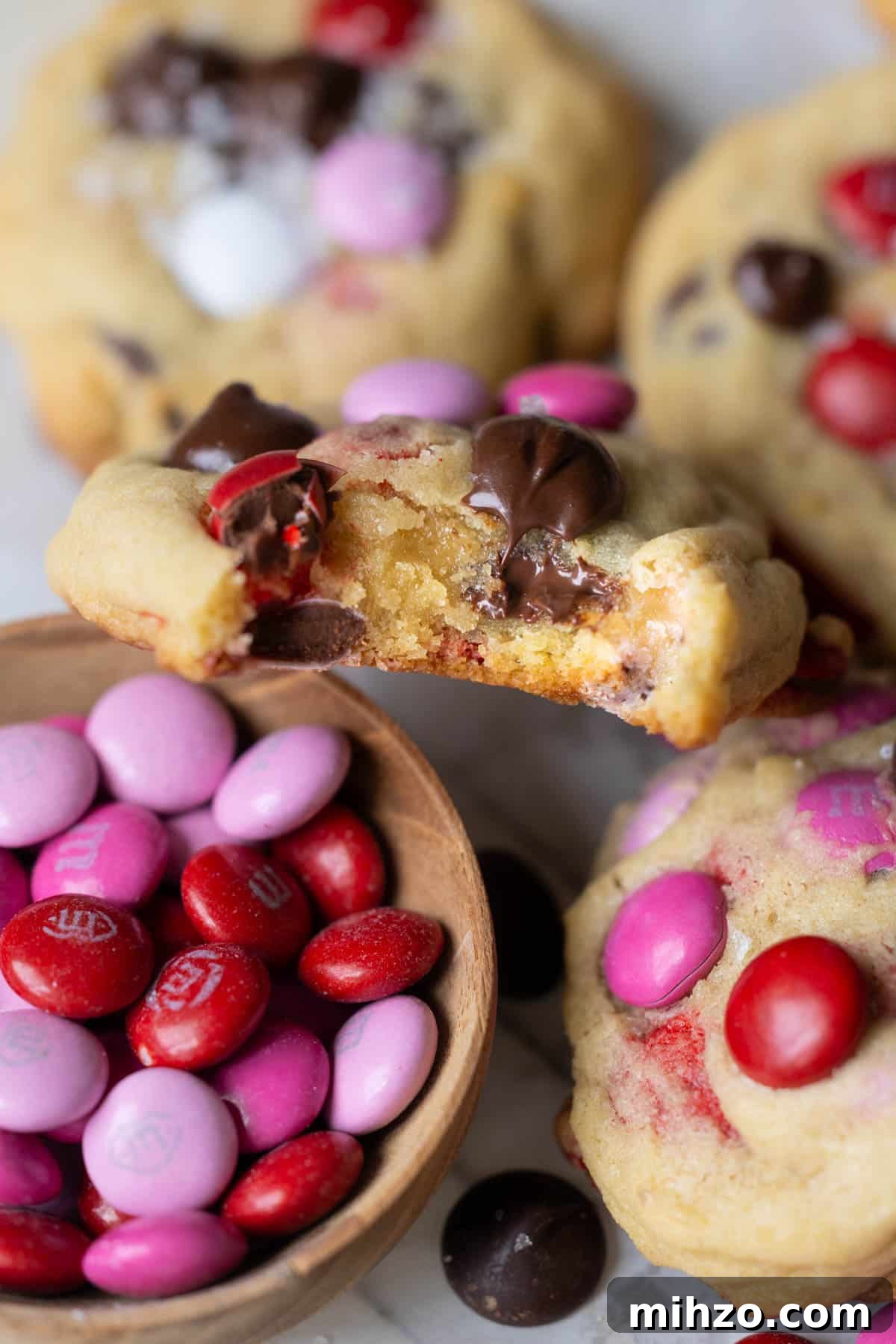 Valentine’s Day M&M Cookie Recipe: Festive Chocolate Cookies 7 an up close image of a bite taken out of a cookie made with M&Ms and chocolate chips.