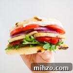 A hand holding up a halloumi sandwich.
