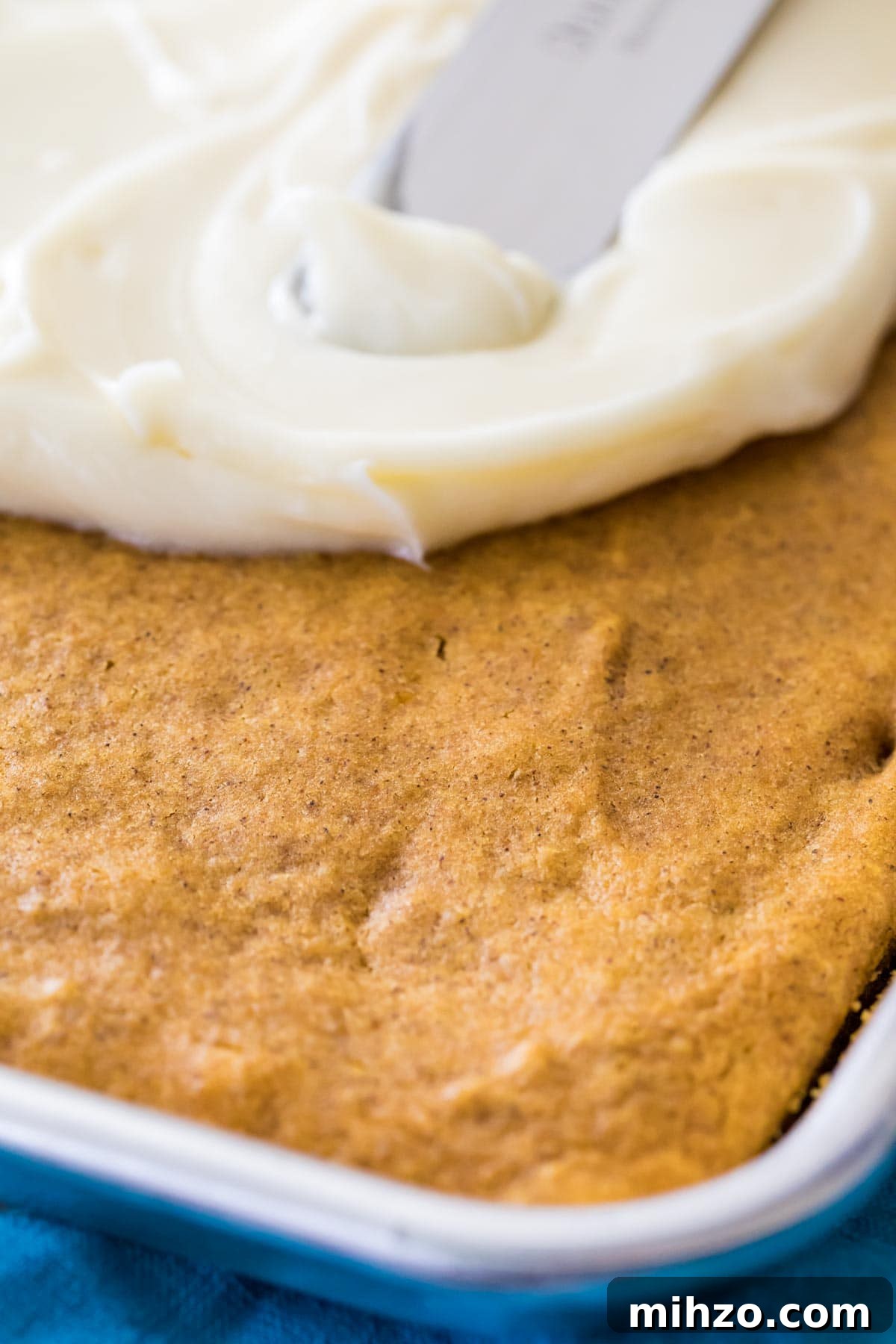 Cream cheese frosting being spread over bars.