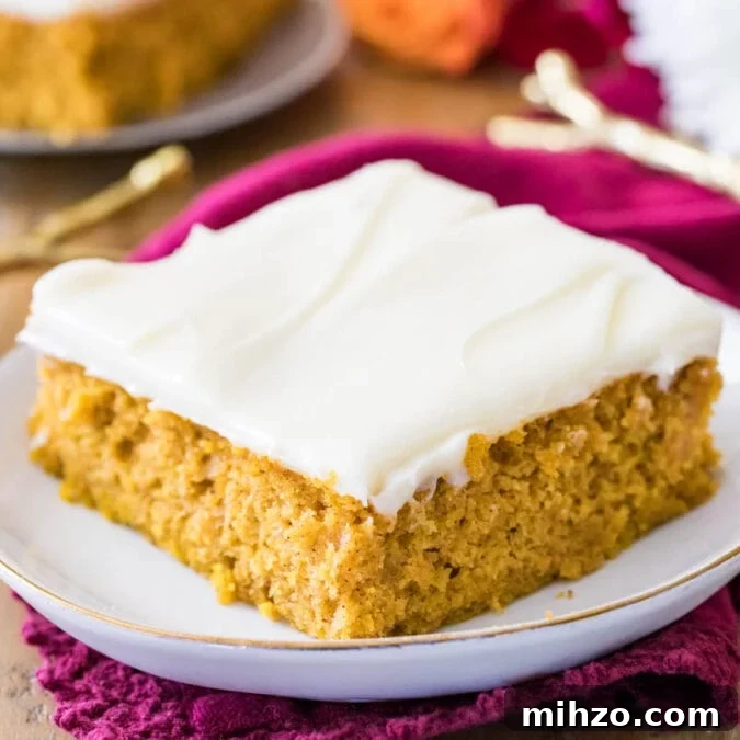 Pumpkin bar frosted with cream cheese frosting on a white plate.
