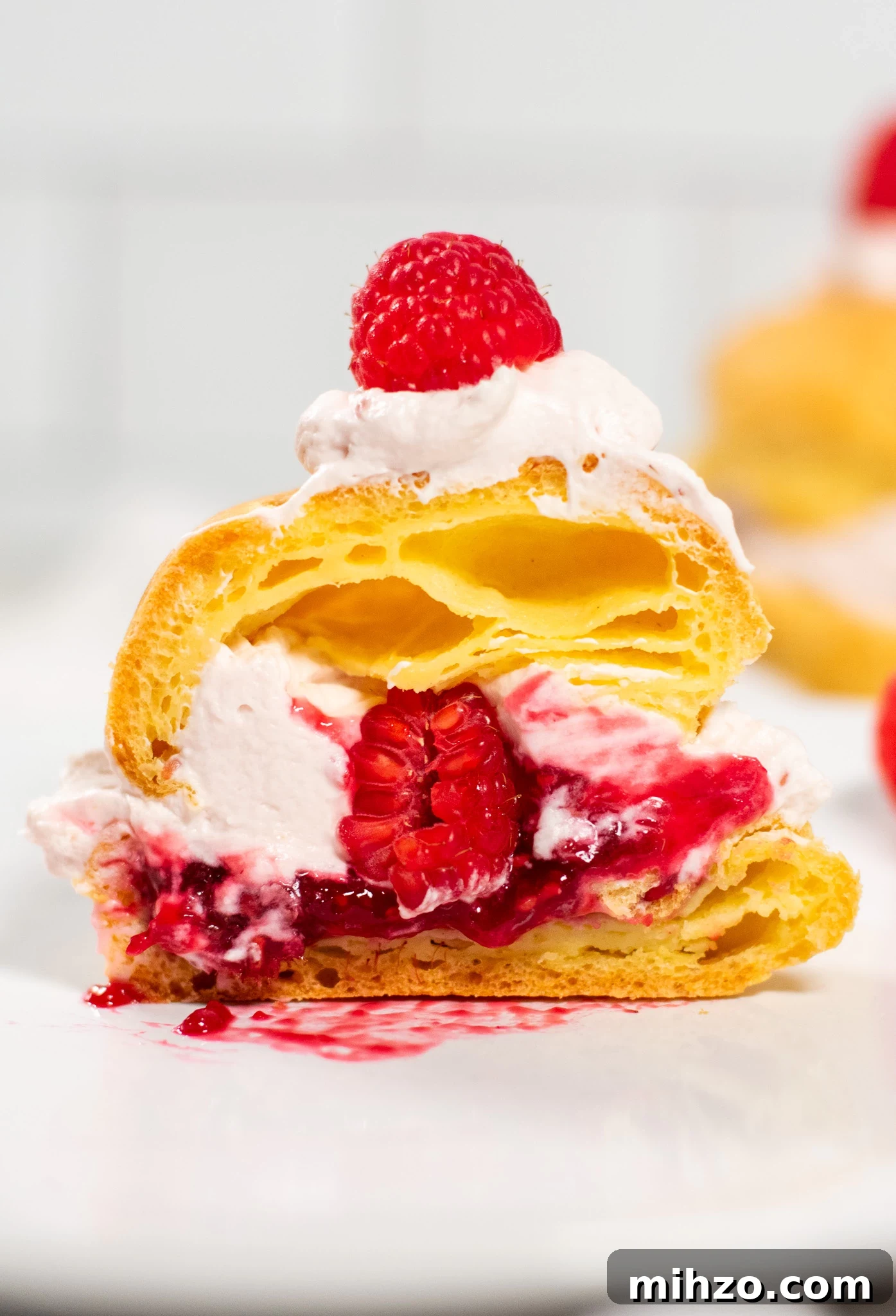 Raspberry Choux Pastry Fastelavnsboller Recipe 6 A cross section of a choux pastry bun filled with raspberry cream cheese whipped cream and raspberry jam.