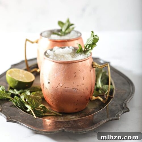 A silver platter holds two copper mugs holding Kentucky Bourbon Mules